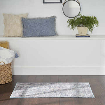 Entryway with Nourison New Concept Light Grey Blue Vintage Rug, dark wood floor, white shelf, and decorative pillows.