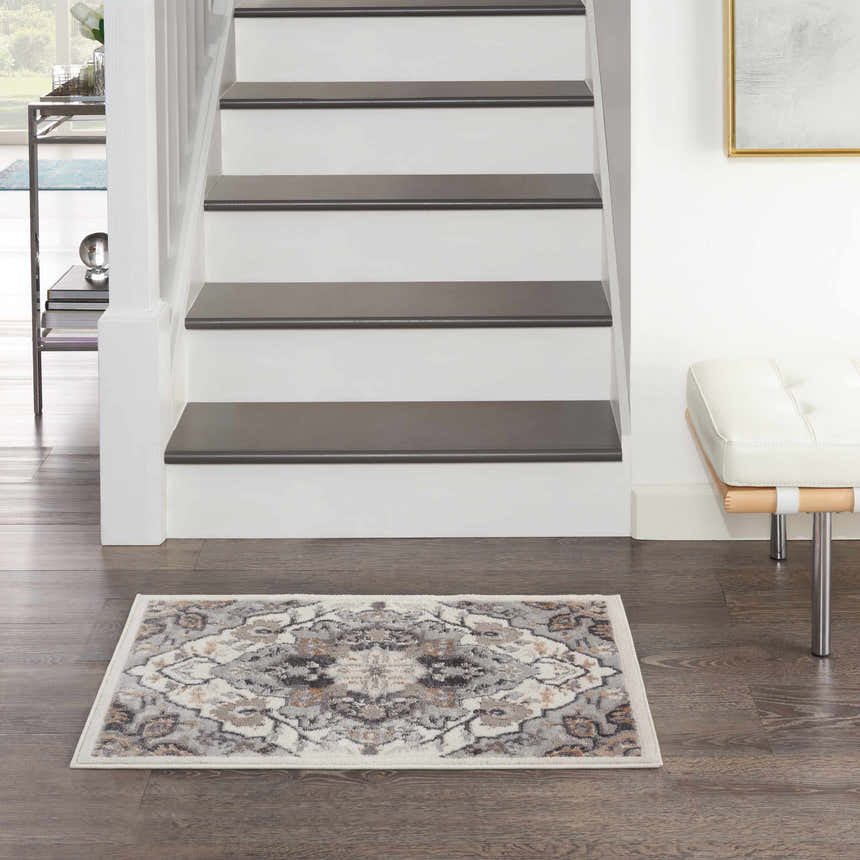 Entryway with Nourison Elation Ivory Grey rug, dark wood floors, white stairs, and a modern white bench. Transitional style.