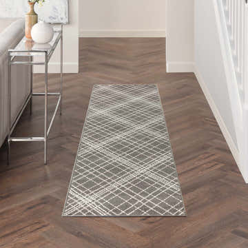 Hallway with Nourison Jubilant Grey Farmhouse runner rug, white geometric pattern, wood floors, and console table.