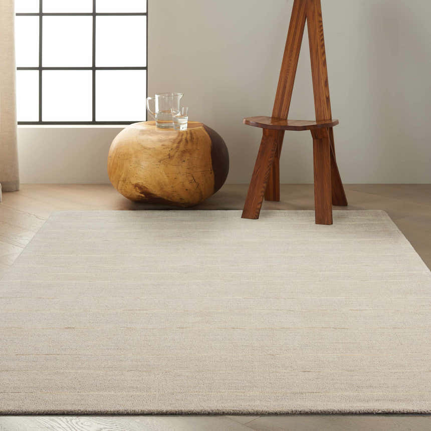 Modern living room scene with a Calvin Klein Halo Grey rug, wood stump table, and unique wooden chair.
