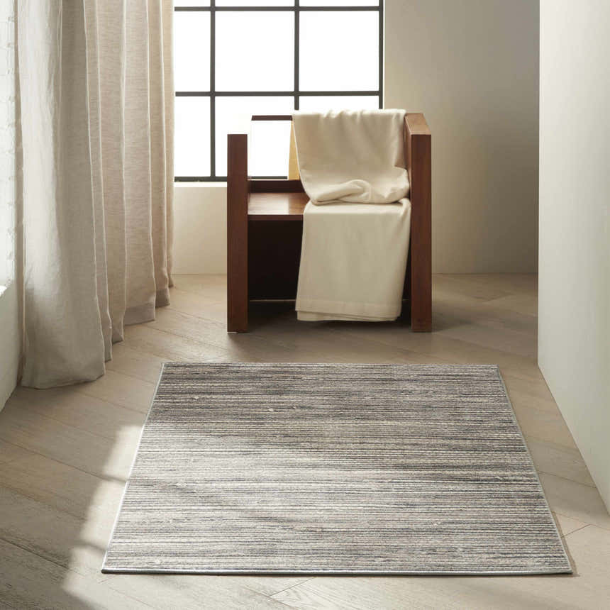 Minimalist room with a Calvin Klein Etched Ivory Grey rug, wood floors, and neutral curtains.