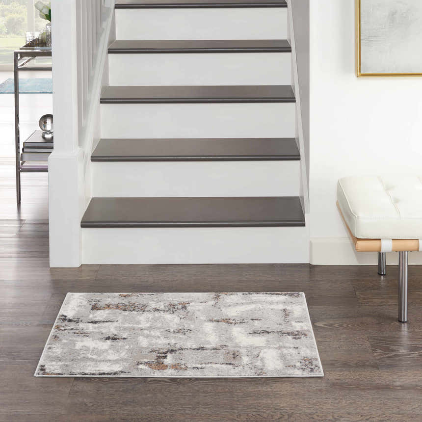 Entryway with Nourison Elation Grey Ivory rug, dark wood floors, white stairs, and a modern white bench.
