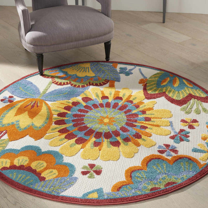 Living room scene with a round Nourison Aloha Multicolor rug under a gray chair on light wood floors.