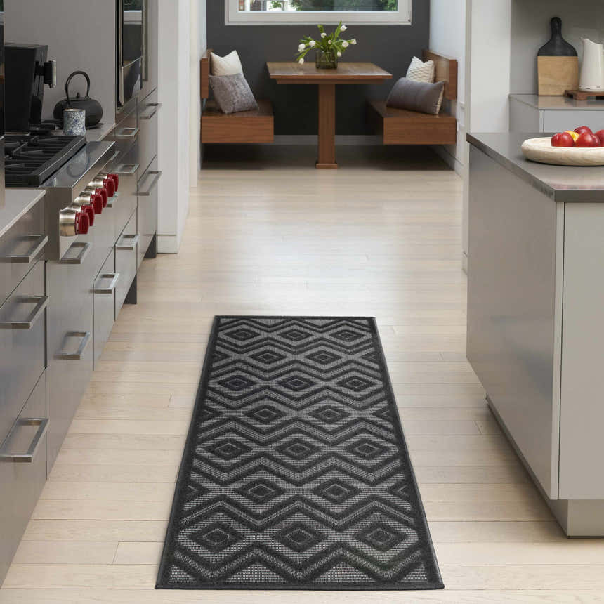 Modern kitchen with a Nourison Versatile Charcoal Black runner rug, light wood floors, and gray cabinets.