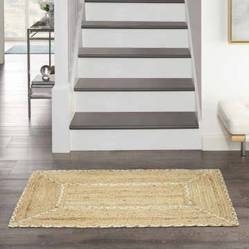 Entryway scene with a Nourison Terrazzo Jute rug, stairs, dark floors, and neutral decor.