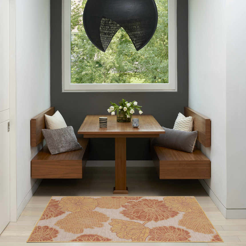 Breakfast nook with Nourison Garden Oasis Coral Tropical Area Rug, wood benches, table, and large window.