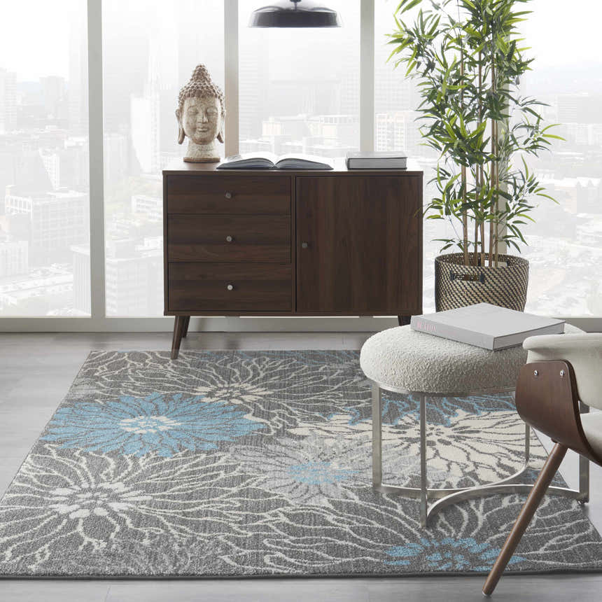 Living room scene with a Nourison Passion Charcoal Blue rug, wood cabinet, Buddha statue, and city view.