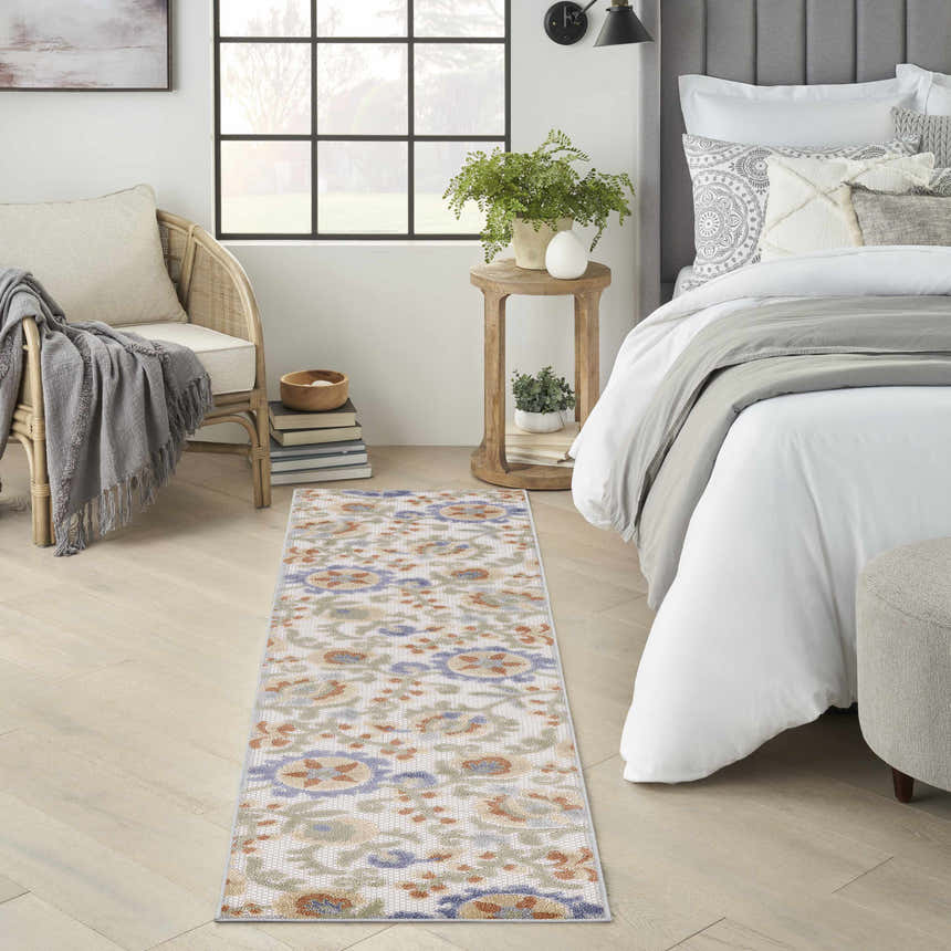 Bedroom scene with a Nourison Aloha Ivory Blue outdoor runner rug on light wood floors.