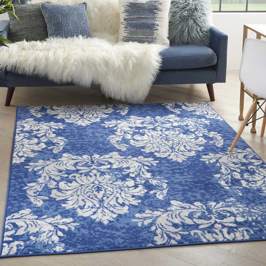 Living room scene with a blue sofa and Nourison Whimsicle Navy Ivory Farmhouse Area Rug.