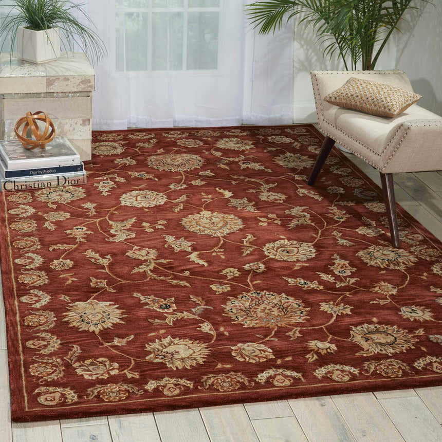 Living room scene with a Nourison 2000 Rust Persian rug, beige chair, and white wood floors.