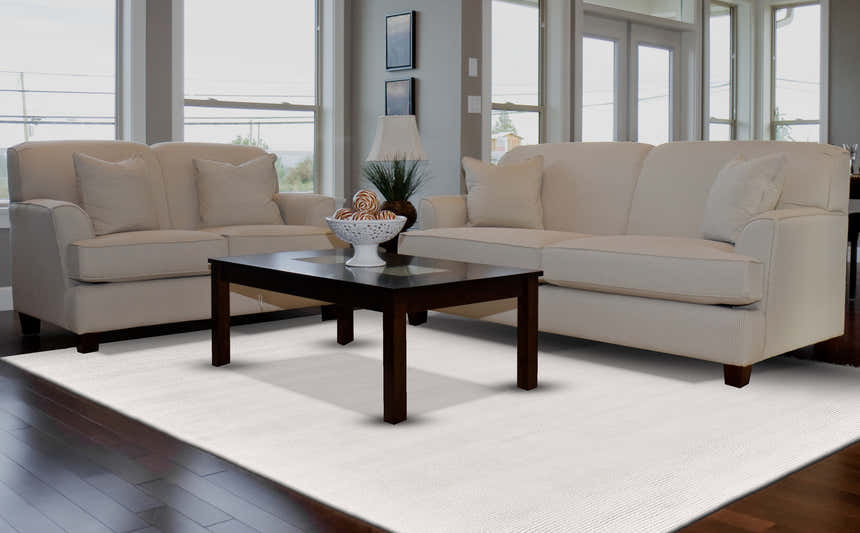 Living room scene with a Feizy Batisse Modern Solid White Area Rug, beige sofas, and a dark wood coffee table. Roomscene-Rectangle