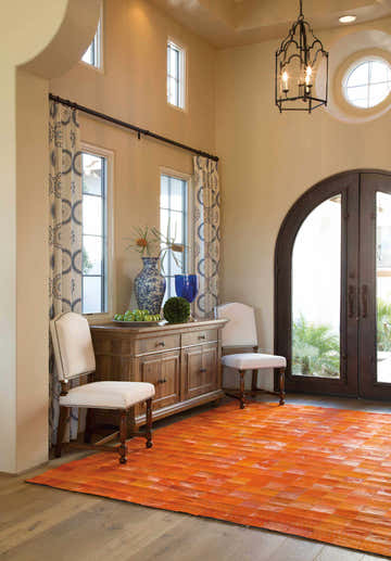 Foyer with Barclay Butera Medley Tangerine rug, wood floors, console table, chairs, and arched doorway.