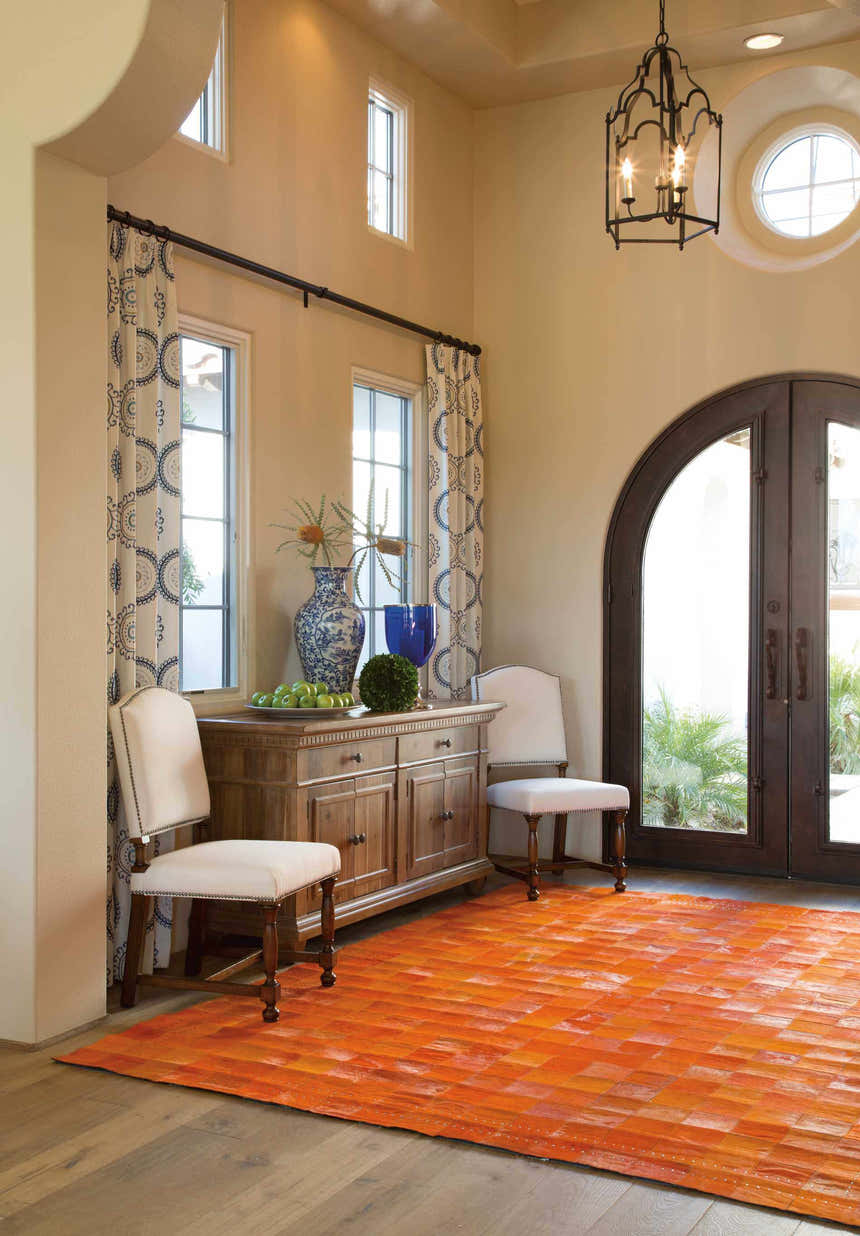 Foyer with Barclay Butera Medley Tangerine rug, wood floors, console table, chairs, and arched doorway.