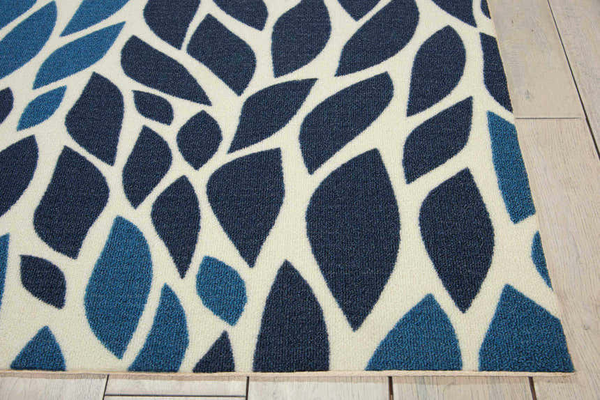 Close up of Nourison Home & Garden blue rug. Mid-century modern design with light and dark blue leaf pattern on a white background.