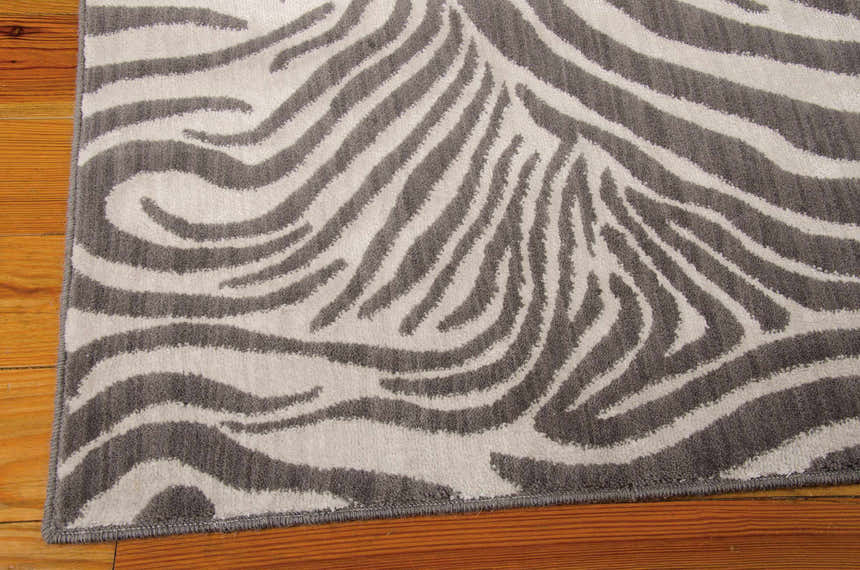 Close-up of Barclay Butera Madagascar Graphite rug showing zebra-like stripes in graphite and ivory on wood floor.