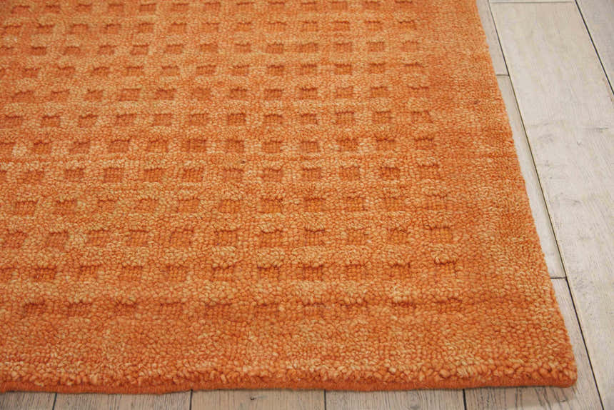 Close-up of the textured Nourison Marana Sunset rug. Orange wool rug with a subtle geometric pattern.