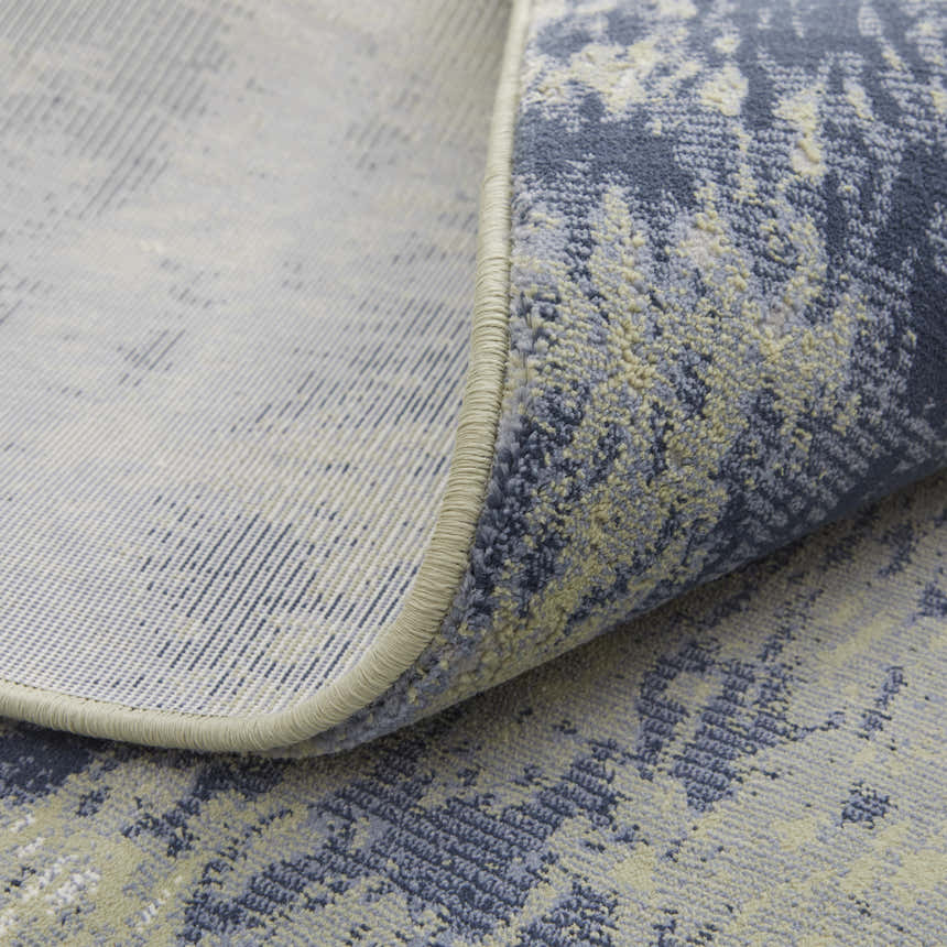 Close-up of the Feizy Clio rug showing its abstract blue, green, and ivory pattern and soft texture. Fold