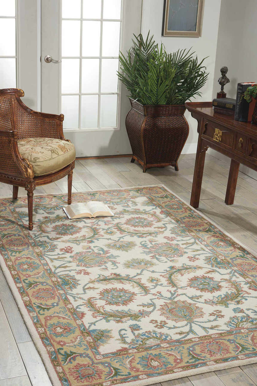Living room scene with Nourison India House Ivory/Gold Persian rug, wood floors, chair, desk, and plant.