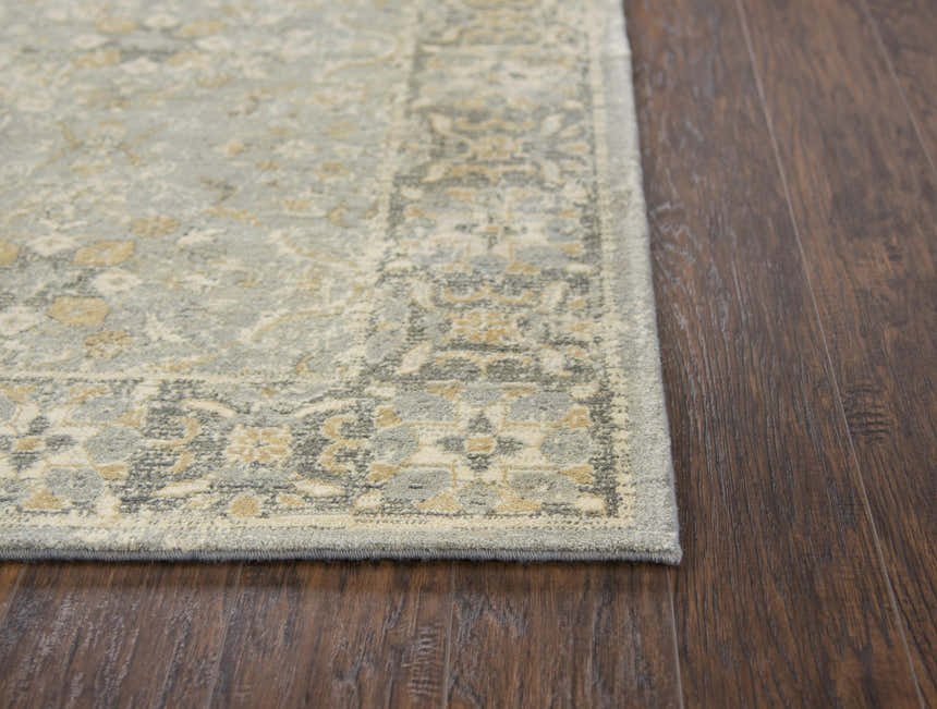 Close-up of Rizzy GS6796 area rug showing beige, gray, and dark red floral pattern and texture on dark wood floor. Corner