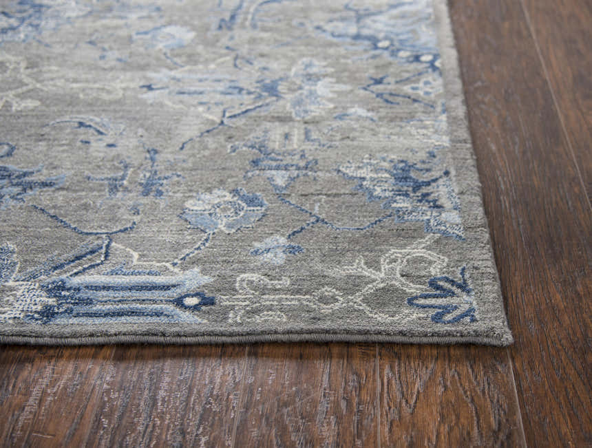 Close-up of the Rizzy GS7225 area rug. Gray wool with a blue floral pattern on a dark wood floor. Corner
