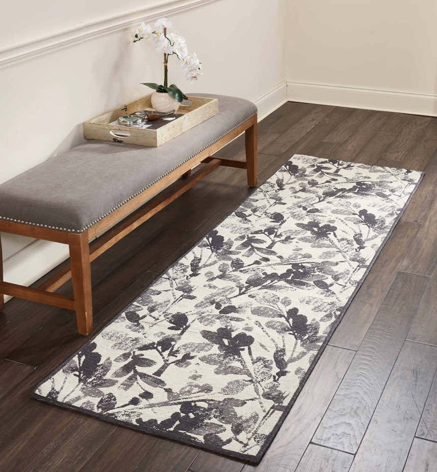 Entryway with Waverly Vintage Lux Graphite rug, gray bench, dark wood floors, and neutral walls.