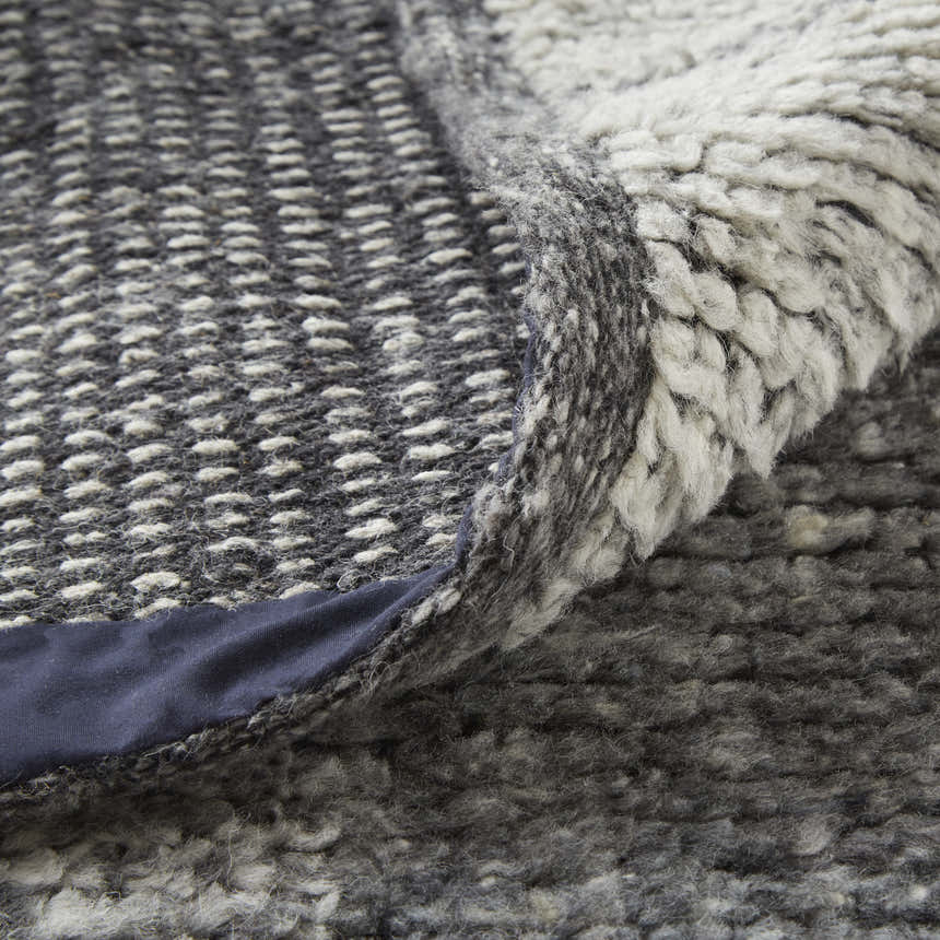 Close-up of the Feizy Alford rug showing the ivory and gray geometric pattern and hand-knotted wool texture. Fold