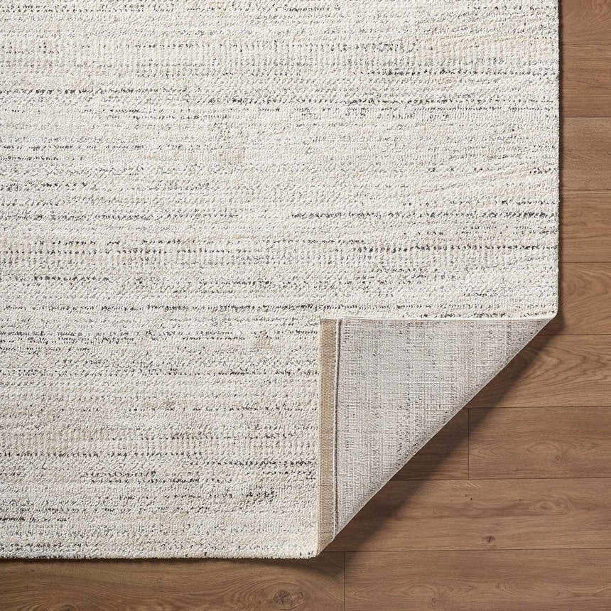 Close-up of the Sezja Beige Luxe Area Rug showing its textured weave, horizontal stripes, and folded corner. Fold