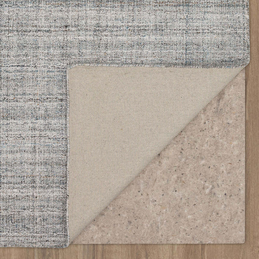 Close-up of the Karastan Haberdasher Silver Area Rug showing its gray, ivory, and blue pattern and texture, plus rug pad. Back