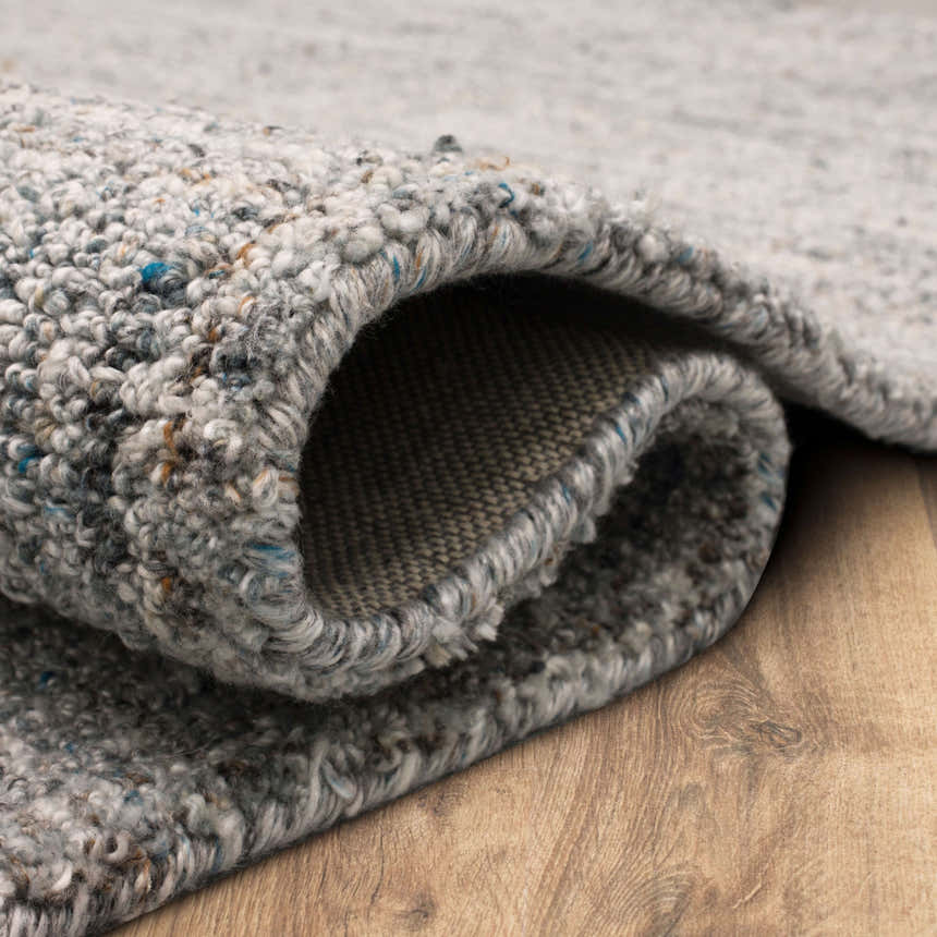 Close-up of the hand-tufted Karastan Haberdasher Silver Area Rug showing texture and backing. Gray, ivory, and blue tones. Fold