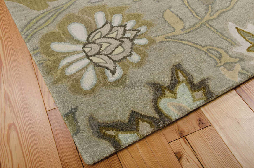 Close-up of the handmade Nourison Jaipur Silver Floral Indoor Area Rug on wood flooring. Wool rug with gray, beige, and white floral design.