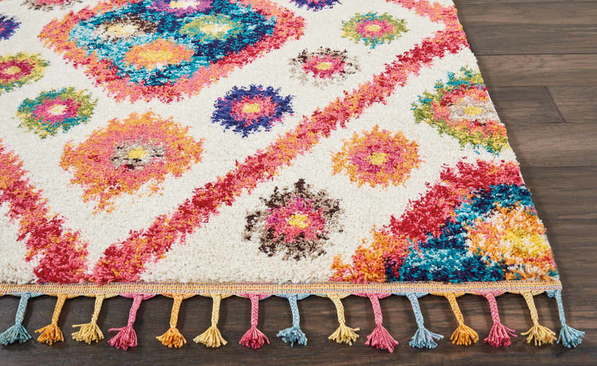 Close-up of Nourison Nomad Ivory Pink Tribal rug with colorful floral and geometric design and decorative tassels.