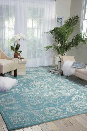 Bright living room with aqua Nourison Opaline vintage rug, light wood floors, white curtains, and neutral furniture.