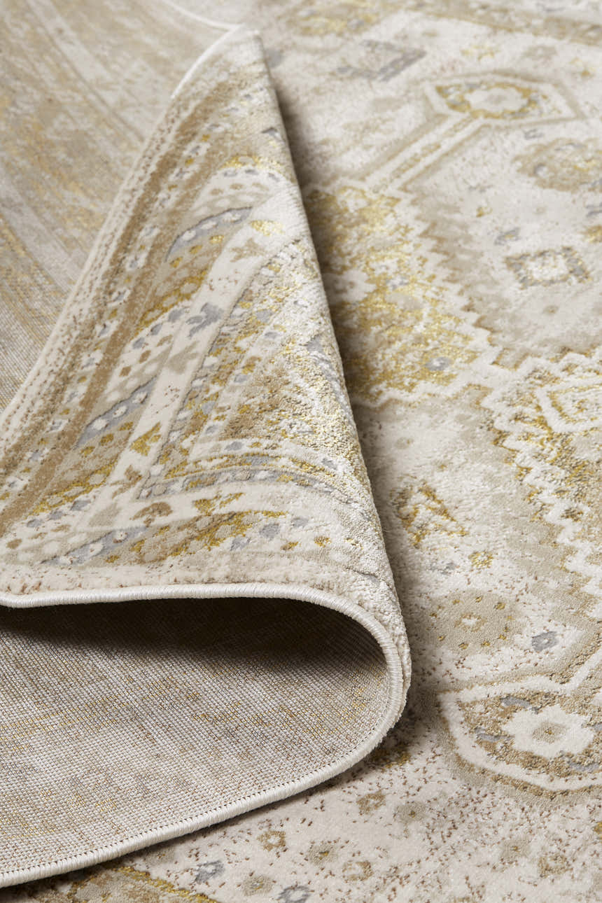 Close-up of Feizy Aura Modern Persian rug in gold and ivory, showing the traditional pattern and jute backing. Fold