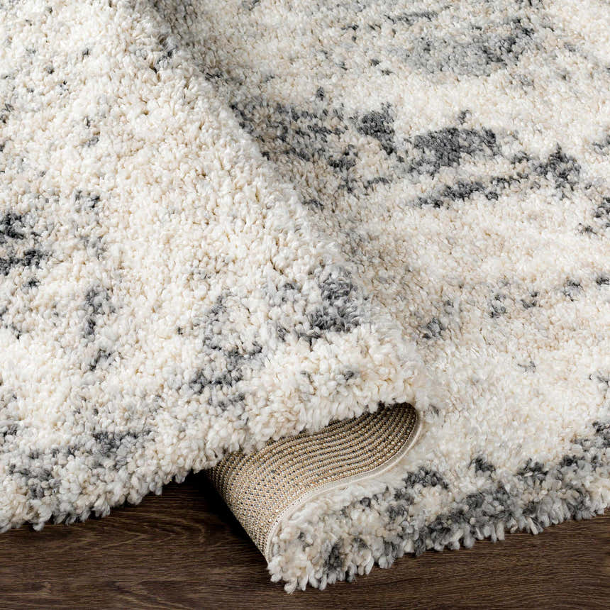 Close-up of the Hilotongan rug showing its plush texture and abstract pattern in cream, black, and gray. Fold