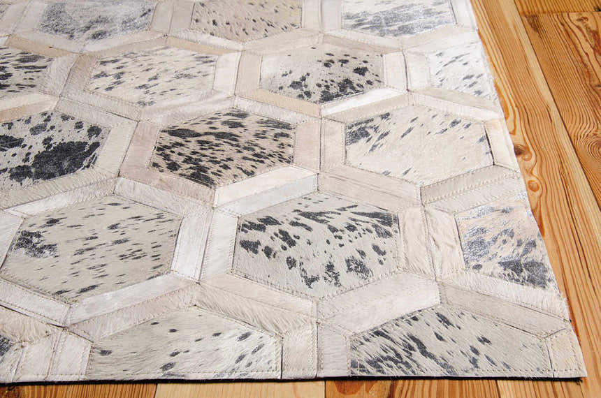 Close-up of Michael Amini City Chic Snow rug. Leather hexagons in snow white with black spots, handmade construction, mid-century style.
