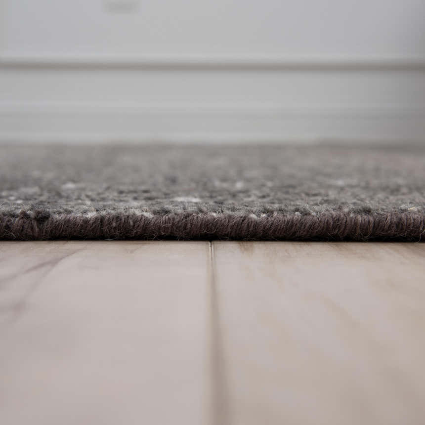 Close-up of the textured, hand-knotted Rizzy HTN720 area rug in gray and ivory on a light wood floor. Pile