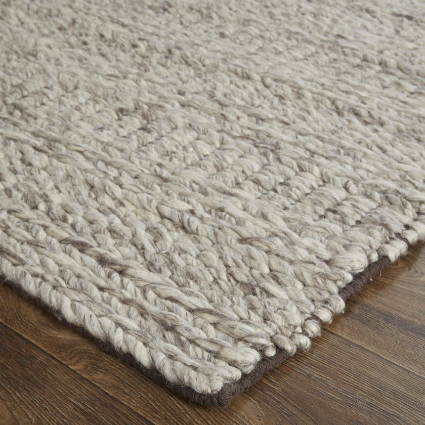 Close-up of the hand woven Feizy Berkeley rug. Ivory, gray, and tan wool rug with chunky, textured geometric pattern. Corner