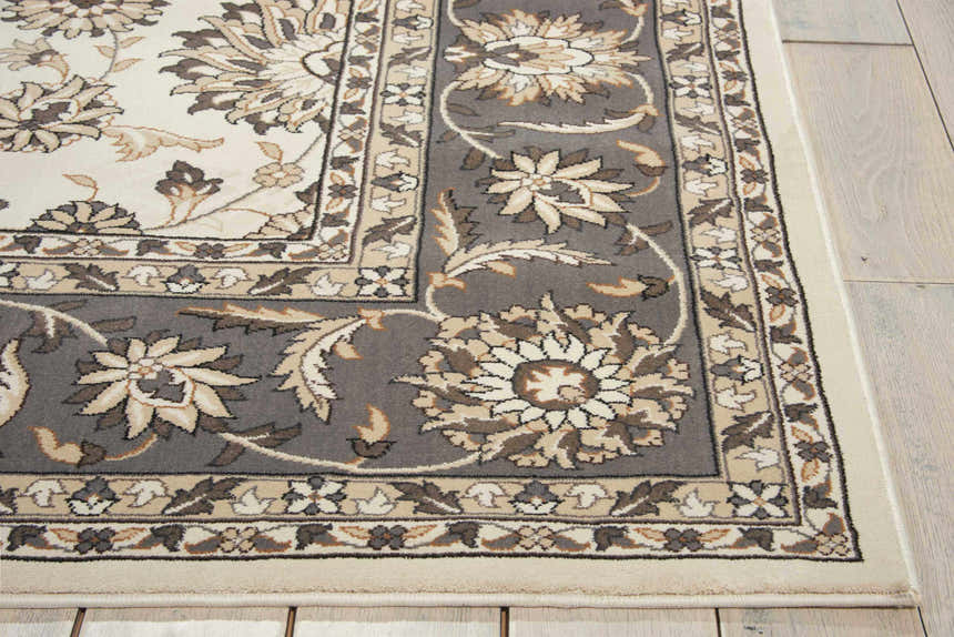 Close-up of Nourison Persian Crown Ivory/Grey rug. Features a floral Persian design in ivory, grey, and chestnut on a wood floor.