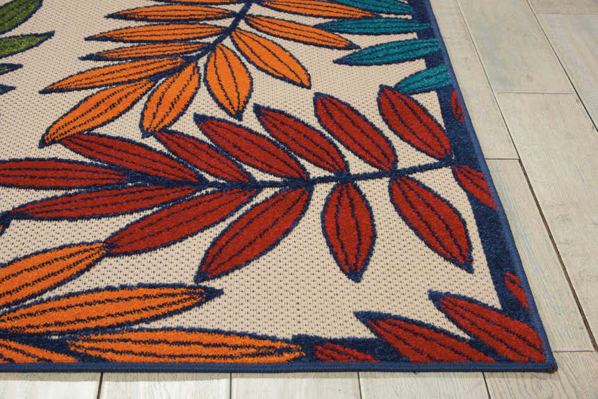 Close-up of Nourison Aloha Multicolor Tropical Area Rug; features orange, red, and teal leaves on a light neutral background.