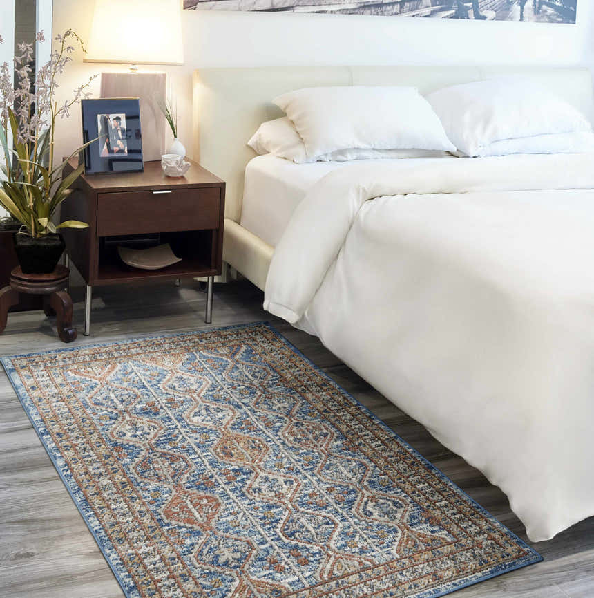 Bedroom scene with Nourison Quarry Blue Multicolor rug, white bedding, and wood nightstand. Contemporary style.
