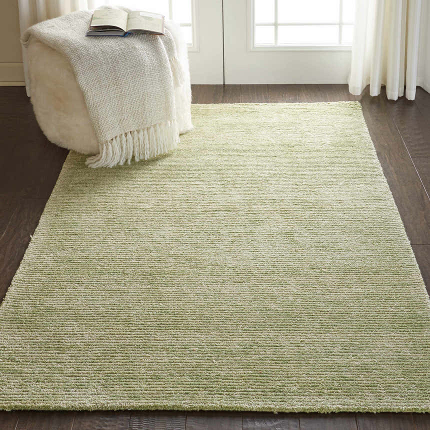 Living room scene with a Nourison Weston Citron rug, white ottoman, wood floors, and sheer curtains.