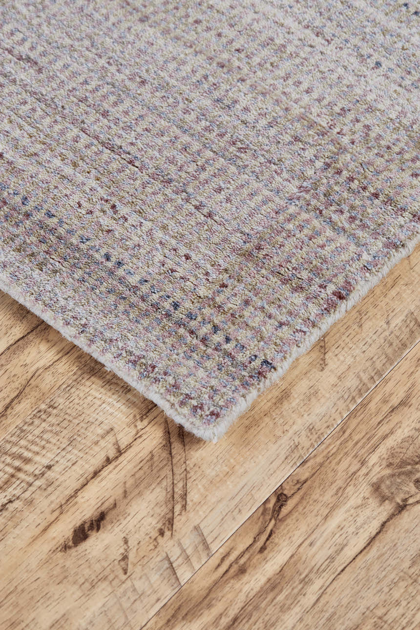 Close-up of the Feizy Milan rug, a hand-woven design in blue, purple, and tan viscose and wool, on a wood floor. Corner