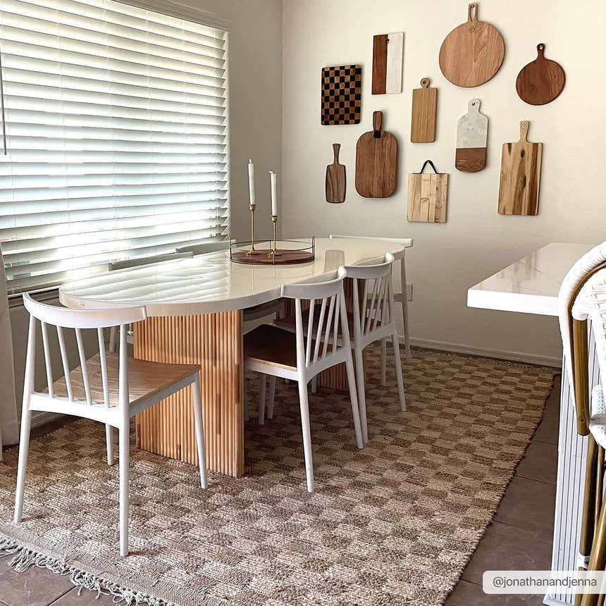 Dining room with a beige Ionut Checkered Jute Area Rug, white table and chairs, and cutting board wall art. Roomscene-Rectangle