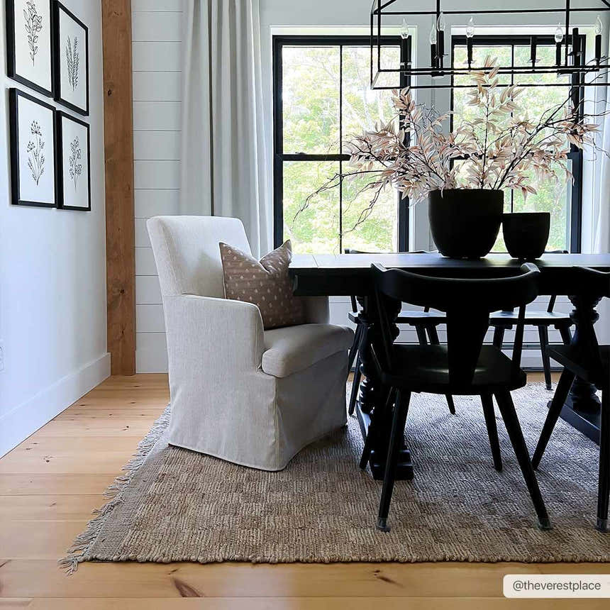 Farmhouse dining room with Ionut Checkered Jute Area Rug, black table and chairs, and a beige armchair. Roomscene-Rectangle