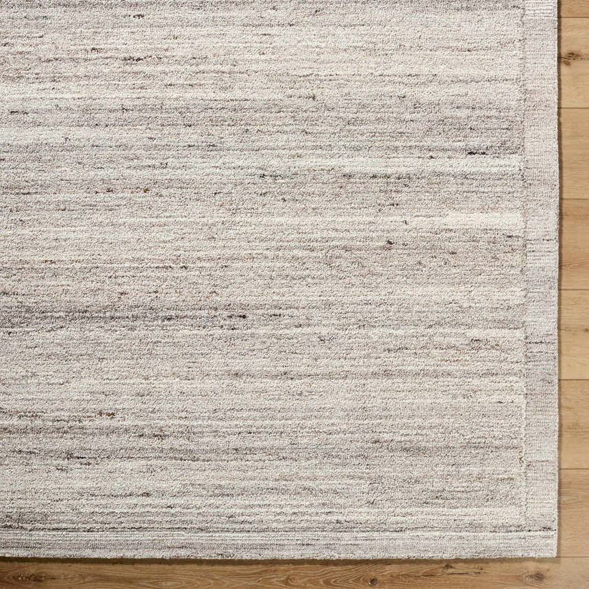 Close up of the Blenda Beige Area Rug. Hand tufted wool rug with beige, charcoal, and gray striations. Corner