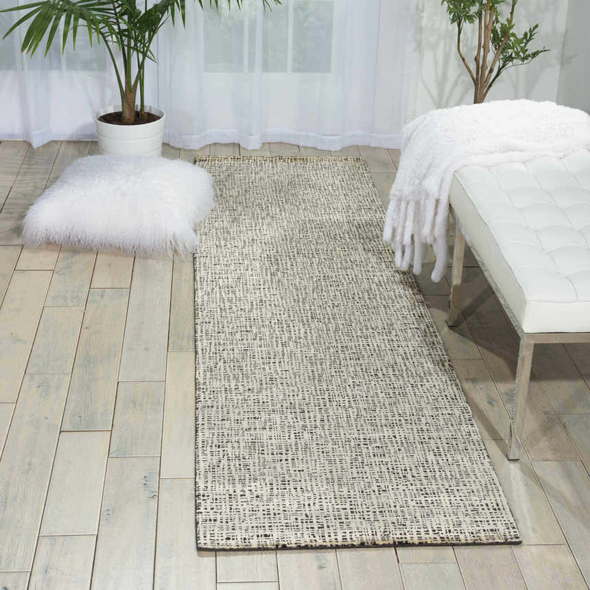 Modern entryway with a Nourison Starlight Midnight rug, white bench, and plants. Neutral tones create a calming space.