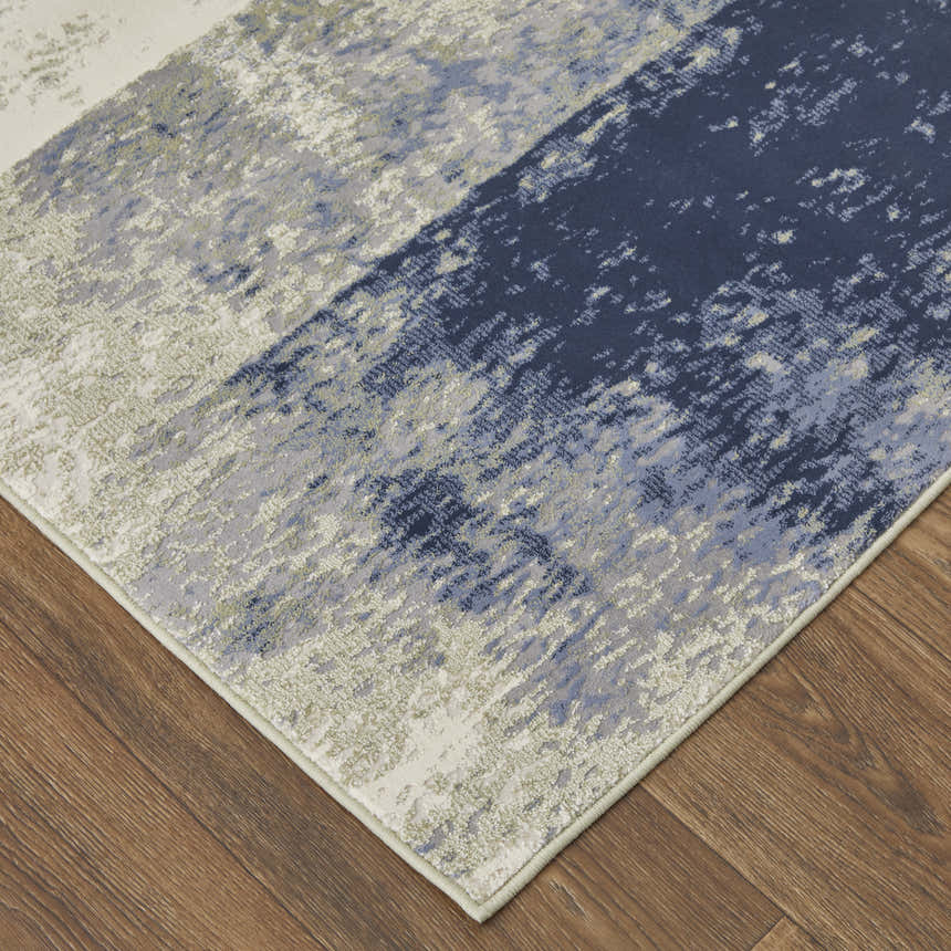 Close up of Feizy Clio rug; abstract design in blue, green, and ivory on a wood floor. Corner