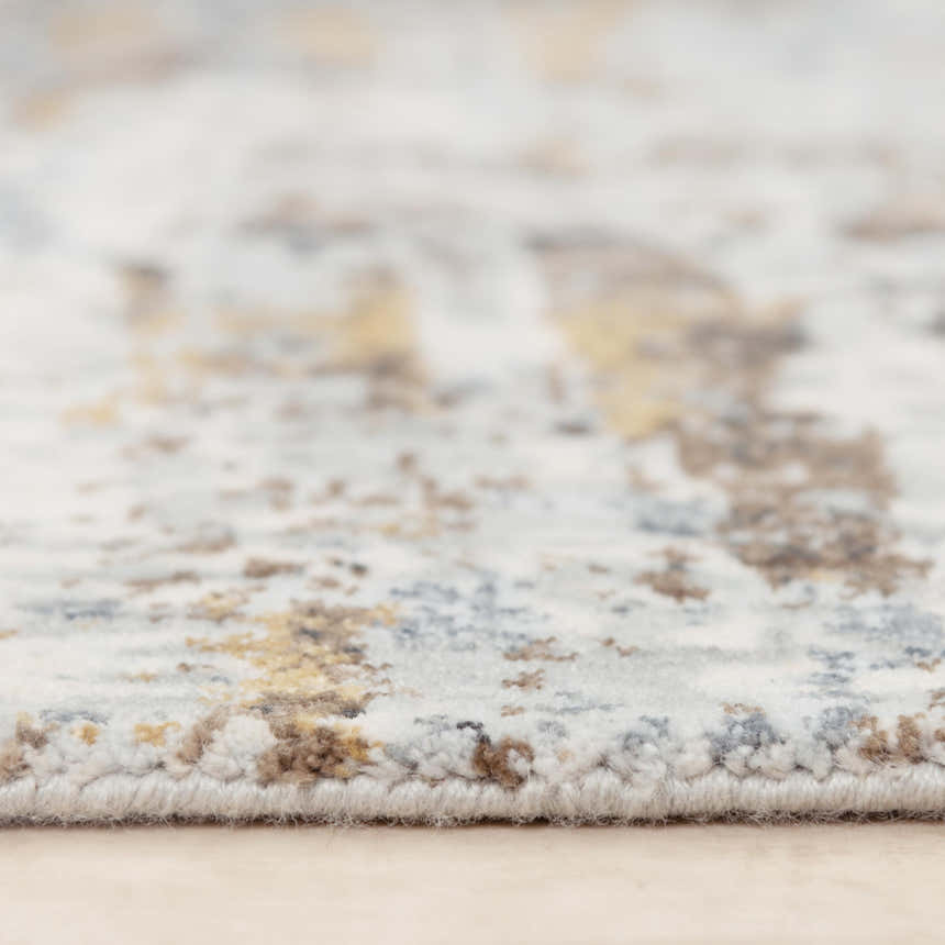 Close-up of the Rizzy JAS732 area rug showing its beige, blue, and brown abstract pattern and textured, machine-woven construction. Pile