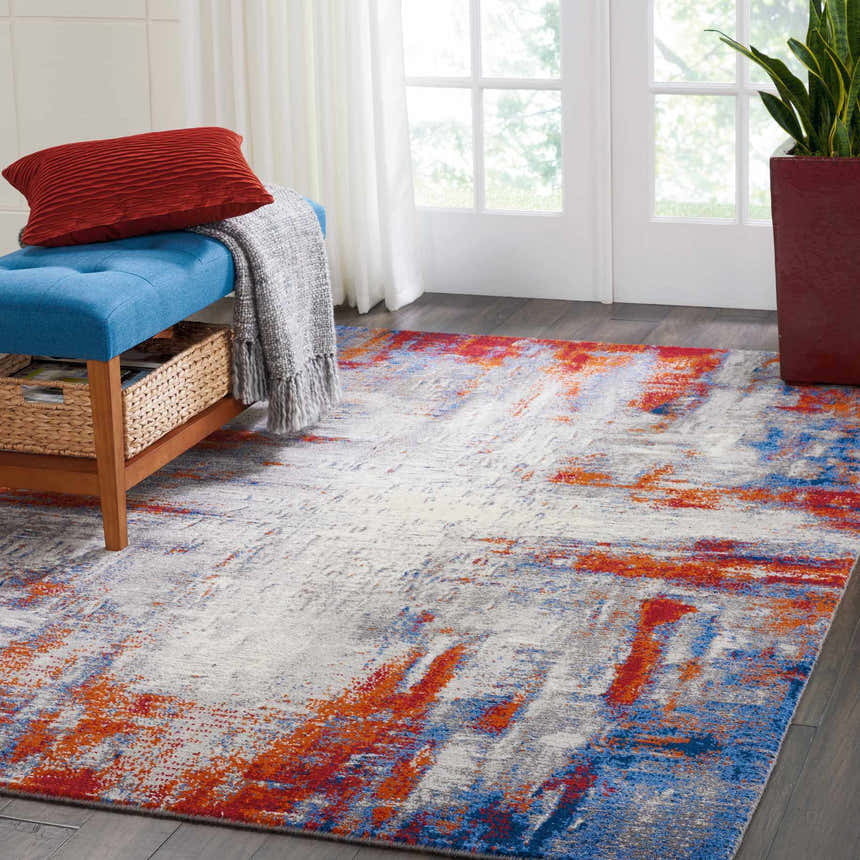 Bright room scene with a Nourison Twilight Ivory Multicolor rug, blue bench, and red accents.