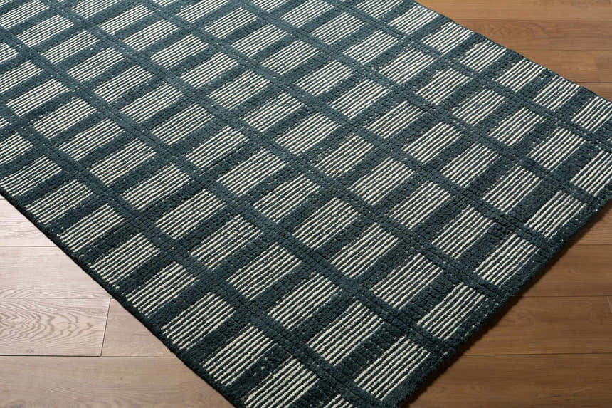 Close-up of the Pumoma rug. Charcoal and ivory striped pattern on a hand-tufted, 100% wool rug. Modern, minimalist design. Corner